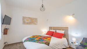 Ein Schlafzimmer mit einem Bett, einem Fernseher, einer Wandleuchte und einem Bild.