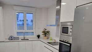 Una cucina moderna con mobili bianchi, un frigorifero in acciaio inossidabile, un forno integrato e una finestra sopra il lavello.