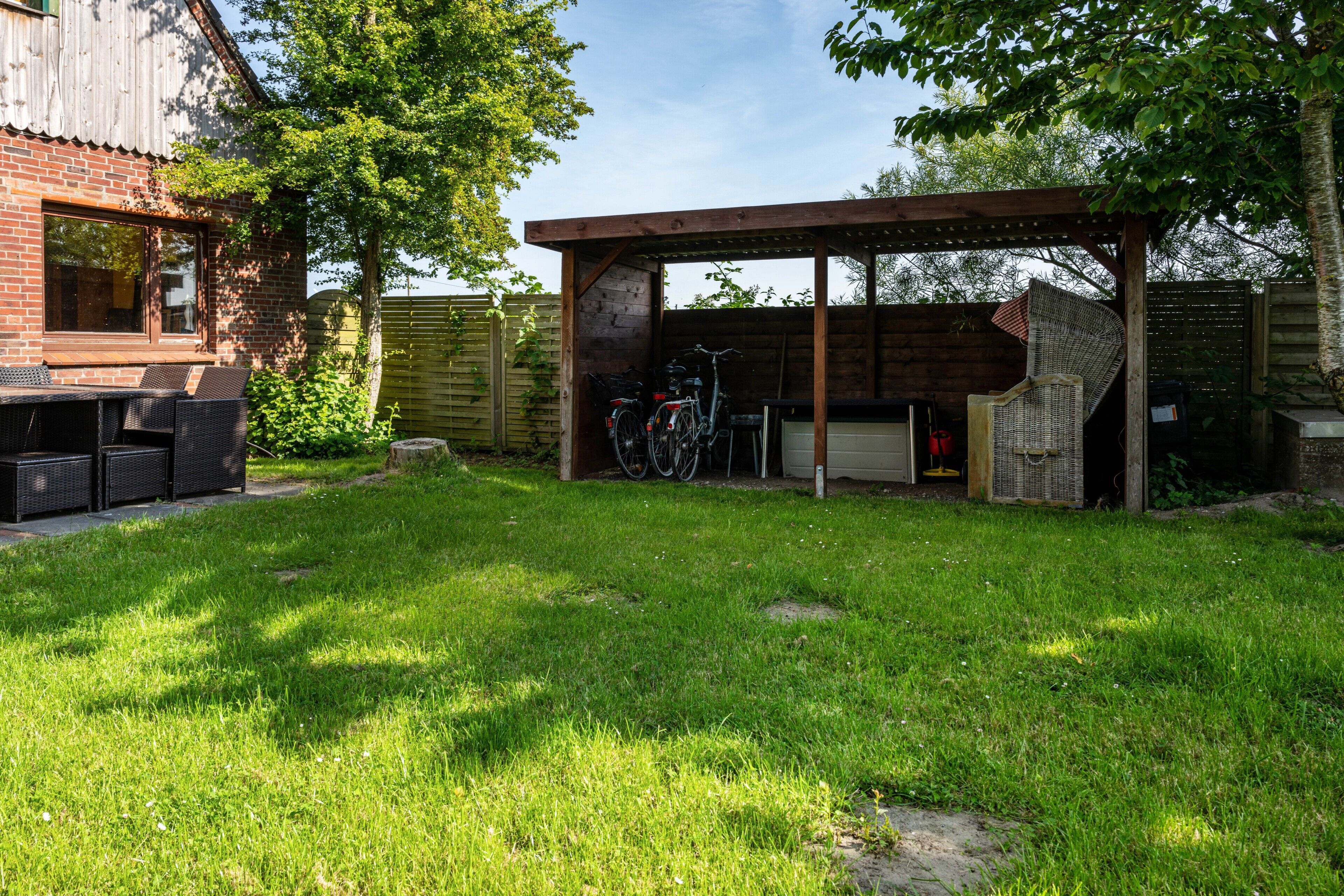 A backyard with a patio area, a covered seating area, and a bicycle rack.