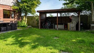 A backyard with a patio area, a covered seating area, and a bicycle rack.
