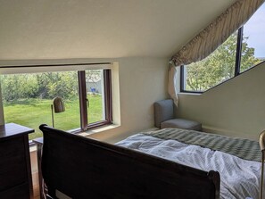 A bedroom with a bed, a chair, a desk, and a window with a view of greenery. - THE ROOKERY, pet friendly in Rosslare Harbour, County Wexford (Tacumshane)