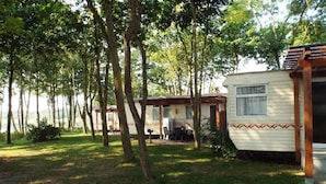 Um camping com veículos recreativos e uma mesa de piquenique em uma área arborizada.