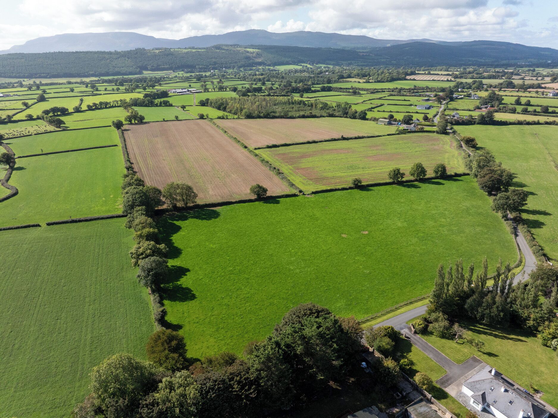 An aerial view of a rural landscape with fields, a road, and scattered buildings.