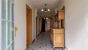 A hallway with a wooden cabinet and a chandelier.