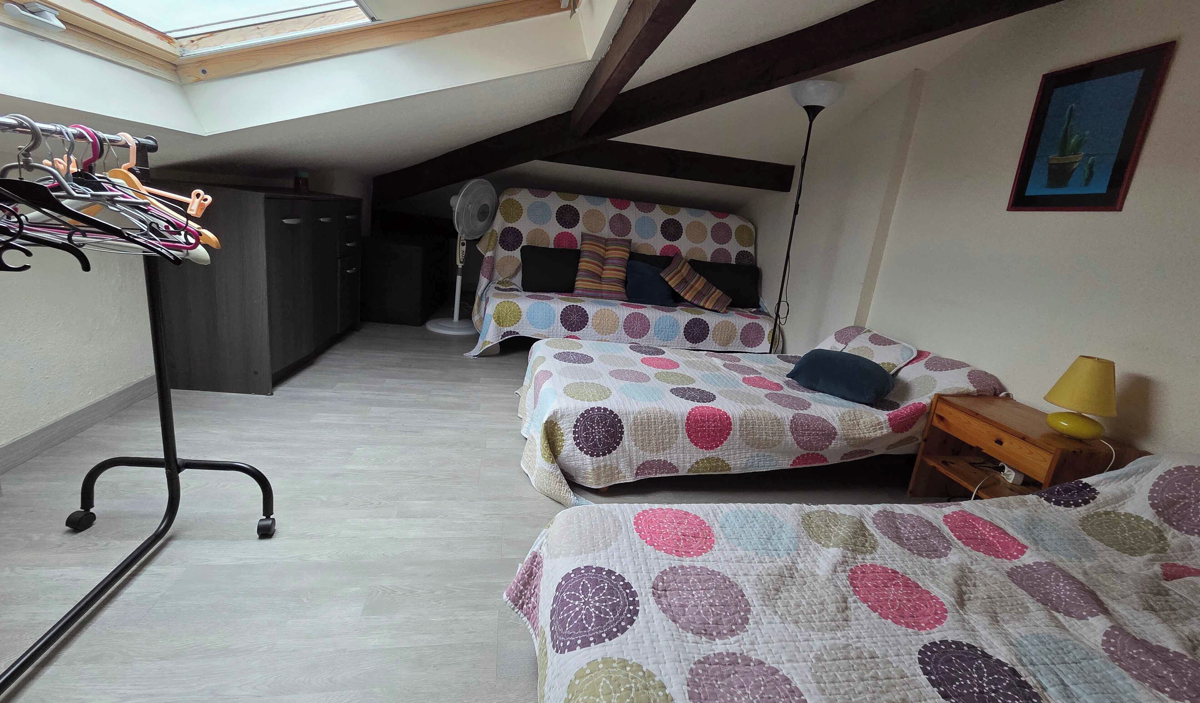 A dormitory room with two beds, a wardrobe, a drying rack, and a skylight.