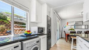 Una cocina moderna con lavadora, refrigerador y comedor con mesa y sillas.
