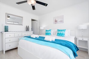 Ein Hotelzimmer mit einem Bett, einem Schminktisch, einem Deckenventilator, einem Spiegel und einem Wandbild.
