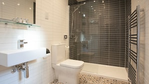 Une salle de bain moderne avec un lavabo, des toilettes et une douche, le tout de couleur blanche.