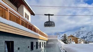 Ein Hotel mit Pool, Skilift und verschneitem Berggrund.