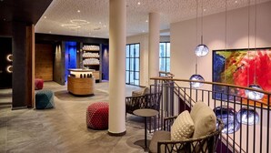 Ein modernes Interieur mit einer Rezeption, einer Sitzecke und einem großen abstrakten Gemälde.