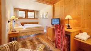 Ein Zimmer mit einem Bett, einem Schreibtisch mit Computer, einem Stuhl, einem Fenster und einem Fernseher.