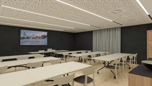 Ein Konferenzraum mit mehreren Tischen und Stühlen, einem großen Bildschirm, der 'petersboden' anzeigt, und einer Holztür.