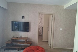 Ein Wohnzimmer mit einem an der Wand befestigten Flachbildfernseher, einer Holz-Unterhaltungseinrichtung und einem roten Sitzsack.