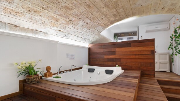 A spa room with a wooden bench, a large bathtub, and a potted plant. - 'Lc Luxury' Apartment with Wi-Fi and Air Conditioning (Bari)
