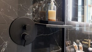 A bathroom with a marble wall, a soap dispenser, and a glass shower enclosure. - 'Salandra' Room with Wi-Fi and Air Conditioning (Bari)