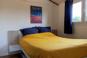 A bedroom with a bed, a nightstand, a poster on the wall, and a window with curtains.