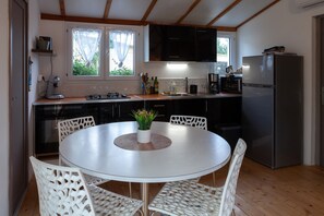Une cuisine moderne avec une table de salle à manger ronde, des chaises blanches et un réfrigérateur.