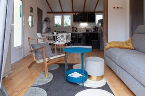 A living room with a grey sofa, a blue side table, a wicker chair, and a small round table.