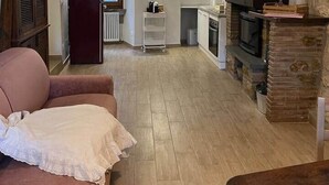 Een compacte leefruimte met kitchenette, televisie en open haard.