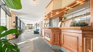 En hotellobby med en bardisk i trä, en receptionsdisk och ett golv av sten.