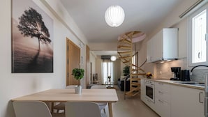 Ett modernt kök med en spiraltrappa, en matplats med bord och stolar samt en stor tavla med ett trädmotiv på väggen.