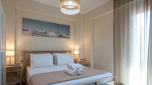 Et pænt indrettet hotelværelse med en stor seng, to sengeborde med lamper, et billedværk på væggen og et vindue med gardiner.