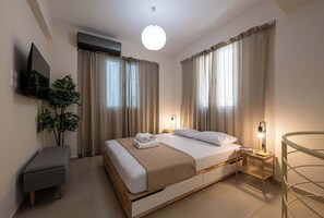 A neatly arranged hotel room with a bed, bedside table, lamp, and a small stool. - Home Easy Kalamata - Central Nest, Prive Parking G1 (Kalamata)