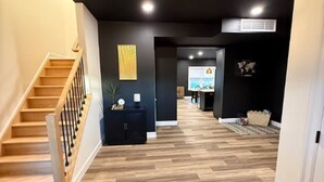 Ein modernes Interieur mit einer Holztreppe, einer schwarzen Wand mit einem dekorativen Element und einem Fischgrätparkett.