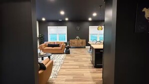 Ein modernes Wohnzimmer mit Sofa, Couchtisch und einer Holzkabine. Es gibt einen Essbereich mit Tisch und Stühlen.