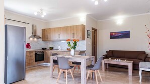 Een moderne keuken met houten kastjes, een marmeren aanrechtblad en een eethoek met een houten tafel en stoelen.