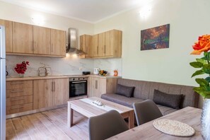 A compact kitchen with wooden cabinets, a built-in oven, and a dining area with a table and chairs. - Villa Georgia 2 - A/C in All Rooms - Fast Wi-Fi - Sleeps 6 (Lefkimmi)