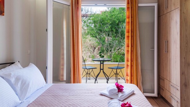 Habitación de hotel con cama, una mesa con sillas y vistas a zonas verdes.