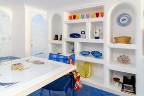 Een kamer met een witte tafel, blauwe stoelen en planken met decoratieve objecten.