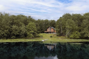 A house by a lake with a dock, surrounded by dense trees. - Luxury Spa Lakehouse • Sauna • Steam Room • Gym (Swan Lake)