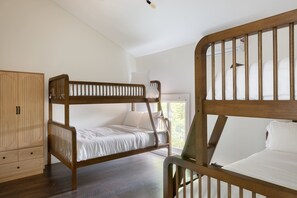 Une chambre avec un lit superposé, une armoire en bois et une fenêtre.