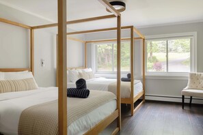 A four-poster bed with a wooden frame, two bedside tables, and a chair.