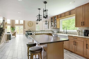 Une cuisine spacieuse dotée d’un grand îlot central, de meubles en bois et de luminaires suspendus.