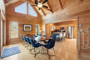 A wooden cabin with a dining area, kitchen, and a staircase. - The Keowee Hideaway• Lakefront • 25 min to Clemson (Seneca)