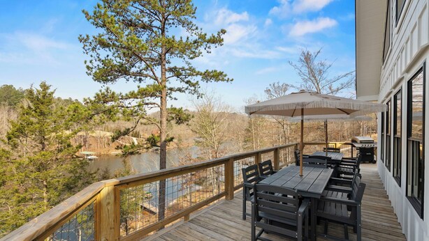 A wooden deck with outdoor furniture and a view of a lake and trees. - The Keowee Hideaway• Lakefront • 25 min to Clemson (Seneca)
