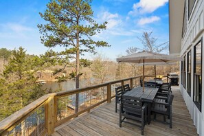 Eine Holzterrasse mit Gartenmöbeln und Blick auf einen See und Bäume.