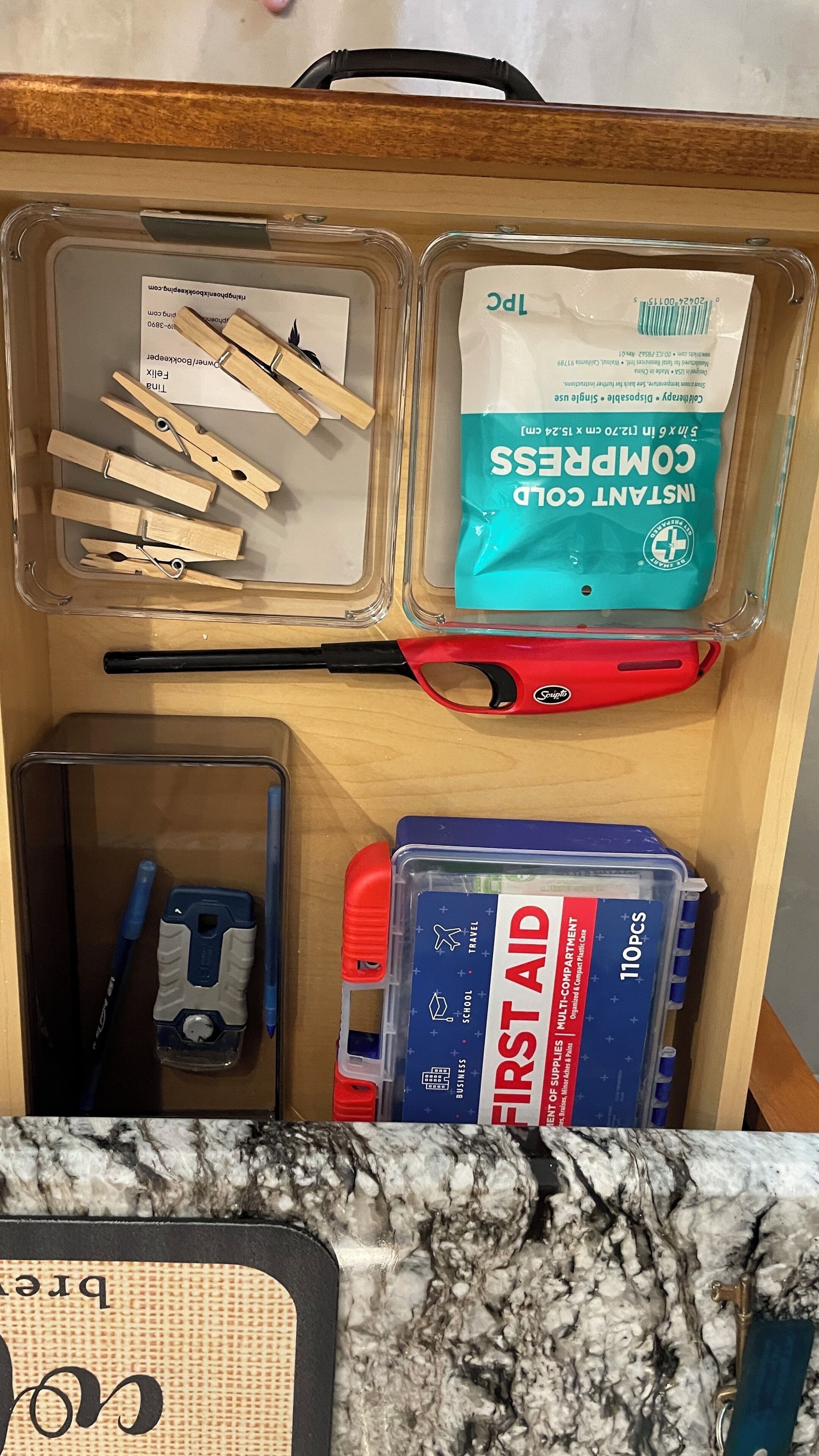 Eine Schublade mit Fächern, die Wäscheklammern, ein Erste-Hilfe-Set und einen kleinen Reiseorganizer enthalten.