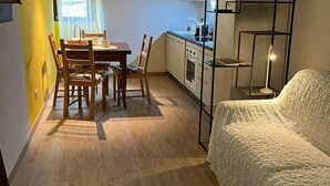 Een kleine woonruimte met een eethoek, kitchenette en een bed.