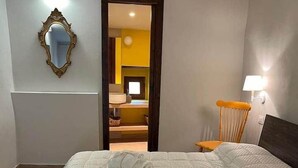 Een slaapkamer met een groot bed, een spiegel, een stoel en een deur naar een andere kamer.