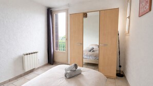 Une chambre à coucher comprenant un lit, un radiateur, une armoire et une porte donnant sur un balcon.
