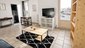 Un salon moderne avec un téléviseur, un coin repas et une vue sur la rue.