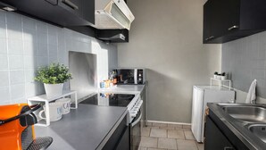 Une cuisine moderne avec des carreaux gris, un four encastré, un four à micro-ondes et un évier.