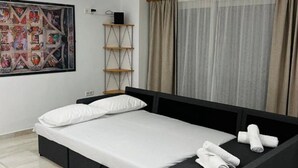 Ein modernes Schlafzimmer mit einem Bett, einer kleinen Couch, einem Gemälde und einem Regal.