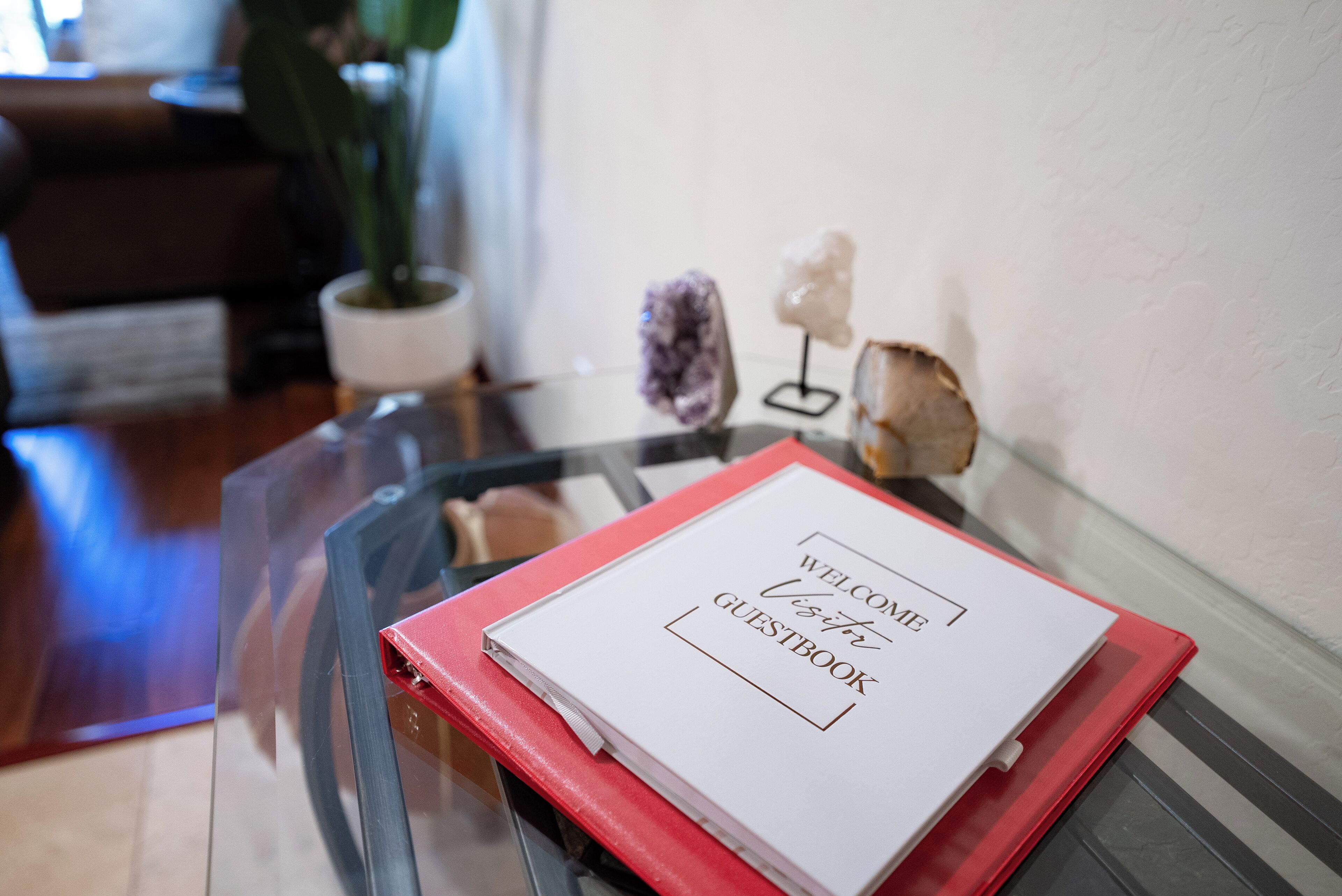 Un libreta de bienvenida sobre una mesa de vidrio, con una carpeta roja a un lado.