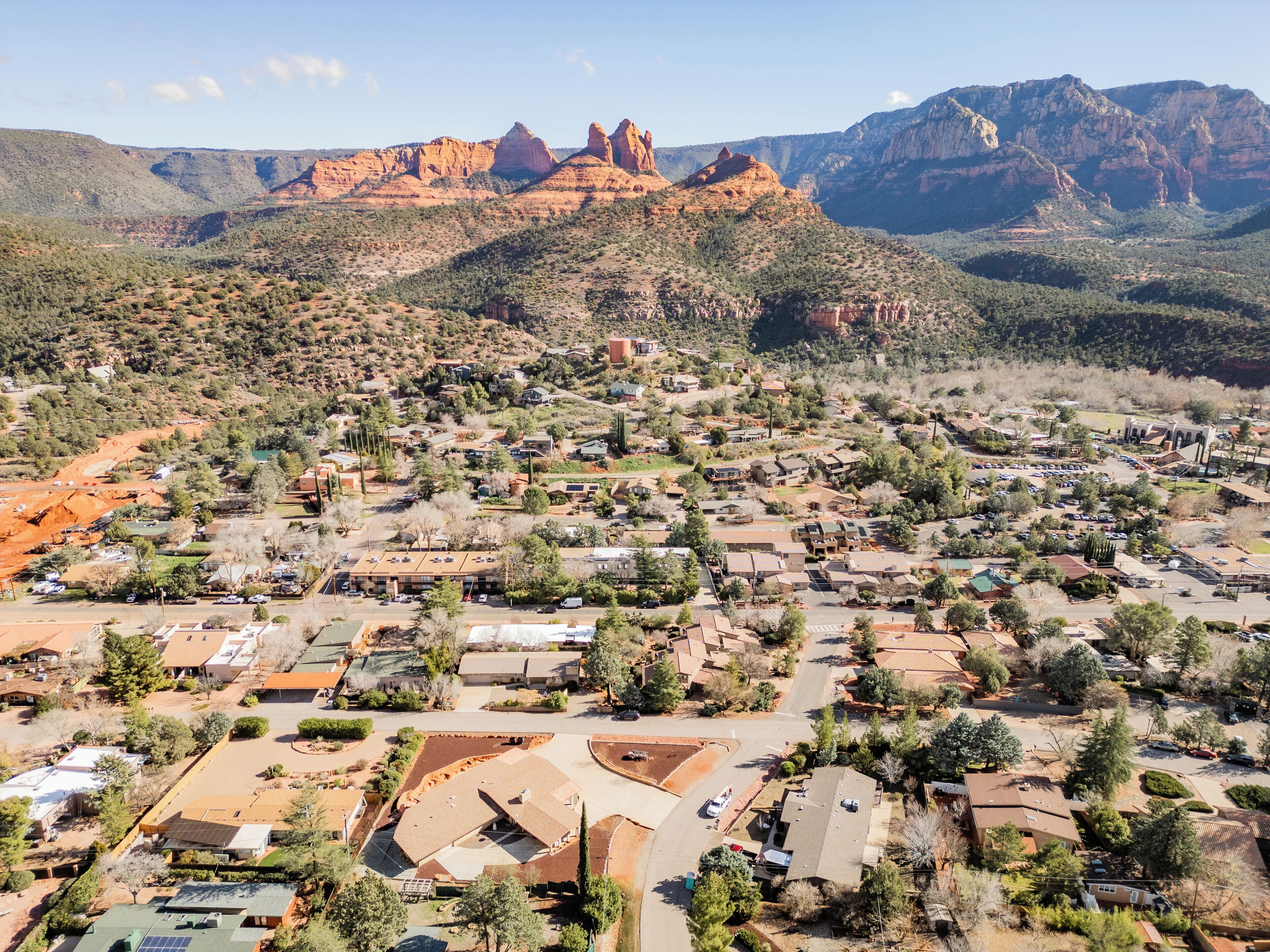 An aerial view of a residential area with houses, roads, and a mountainous backdrop.