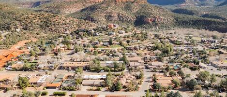 An aerial view of a residential area with houses, roads, and a mountainous backdrop.